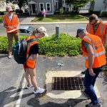 students looking down a storm drain